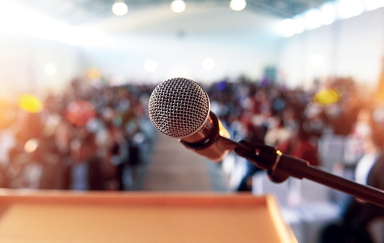 Microphone in front of podium with crowd in the background