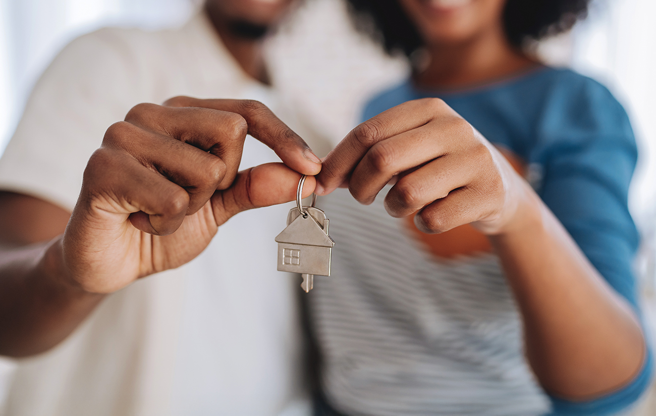 Happy couple buys a house and holds the keys while smiling